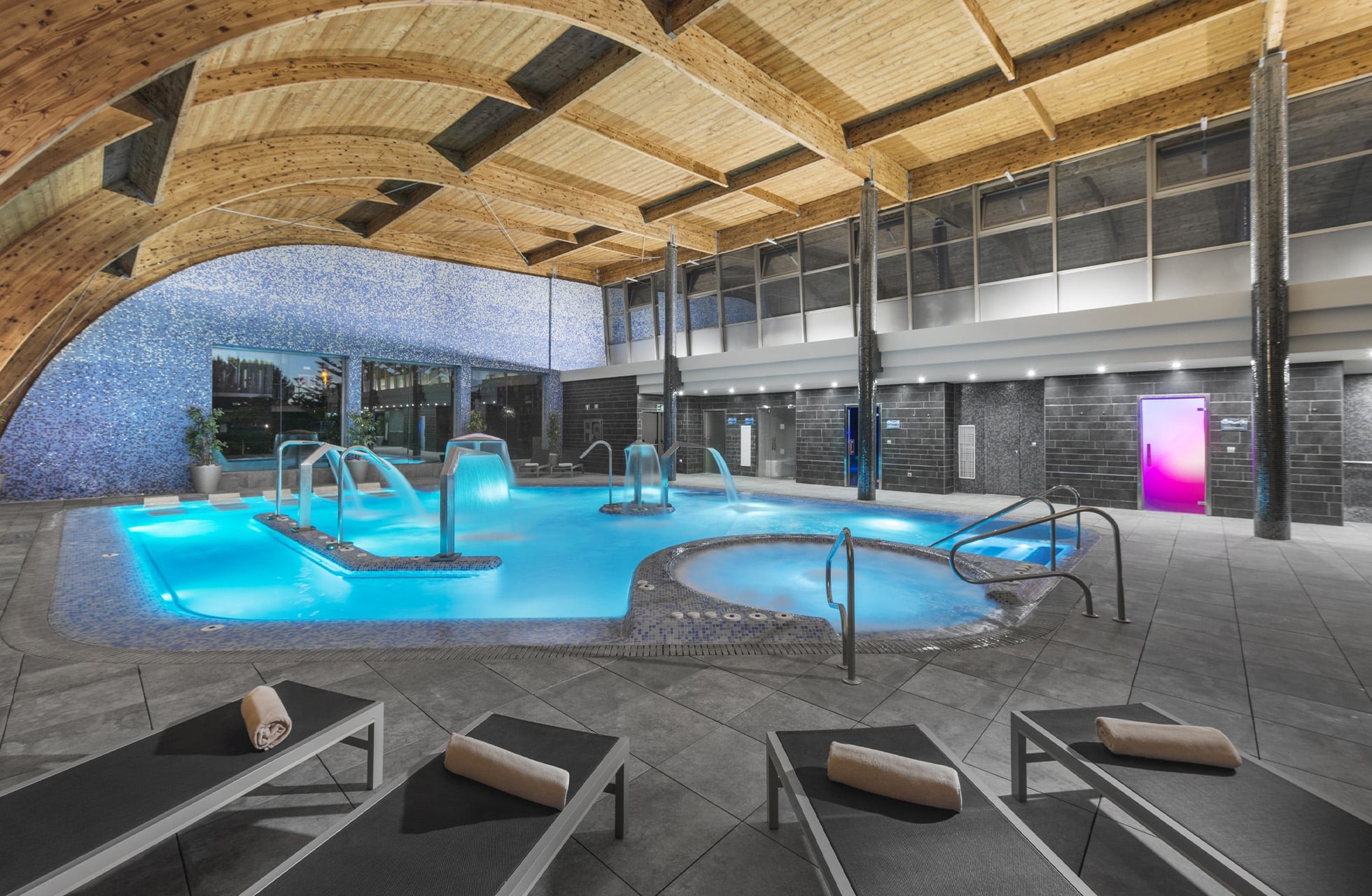 innendørs spa med opplyst basseng, massasjesoner og solsenger