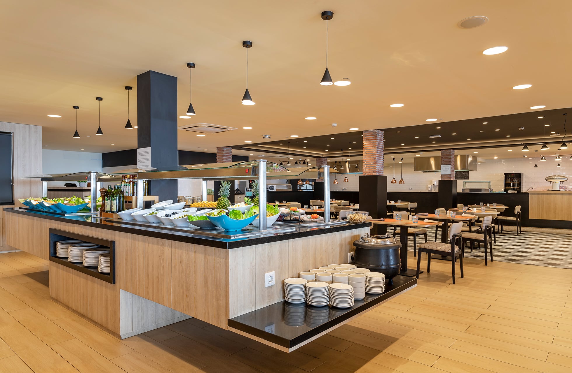 moderne hotelrestaurant med centralt buffetbord, anrettede retter, trædetaljer og lys spisesal i dagslys