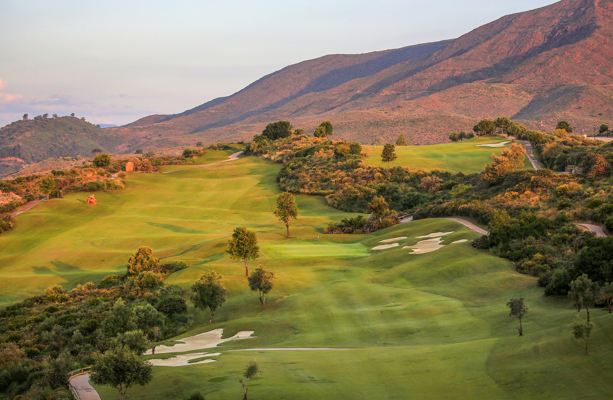 golfbane i morgenlys med bølgende fairways og bunkere