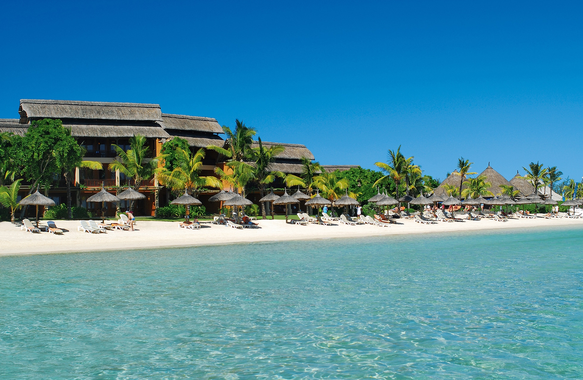 strandutsikt ved heritage awali golf & spa resort med hotellbygninger, solsenger og parasoller langs hvit sandstrand og klart turkist hav