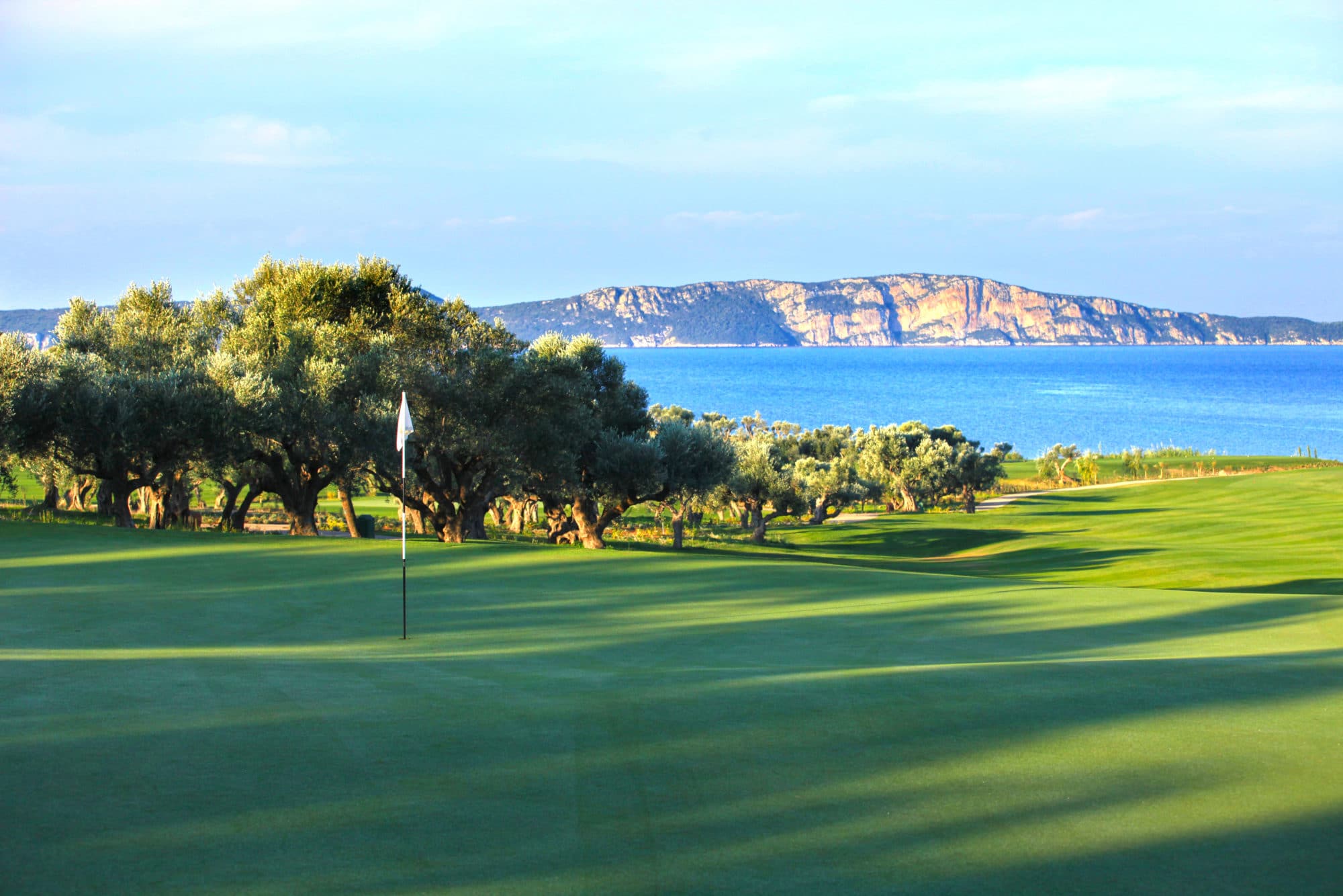 green på the bay course, costa navarino, omgitt av oliventrær med hav og klipper i bakgrunnen