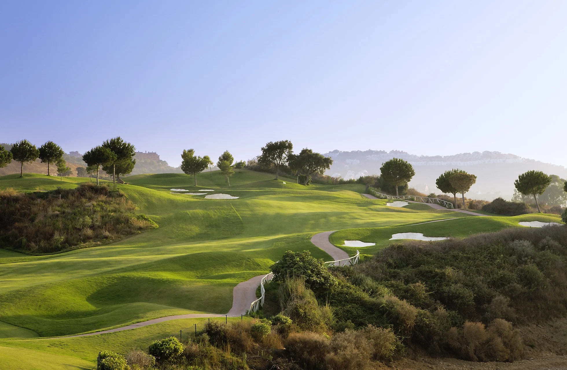 golfgreen ved solnedgang med bunker i forgrunnen