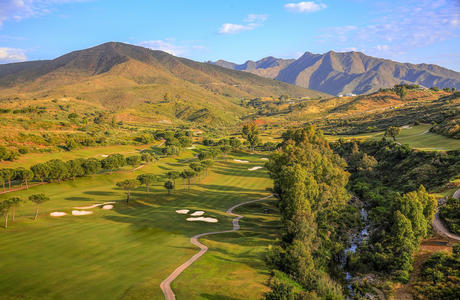 Panoramautsikt over golfbanen med fairways, bunkere og fjell