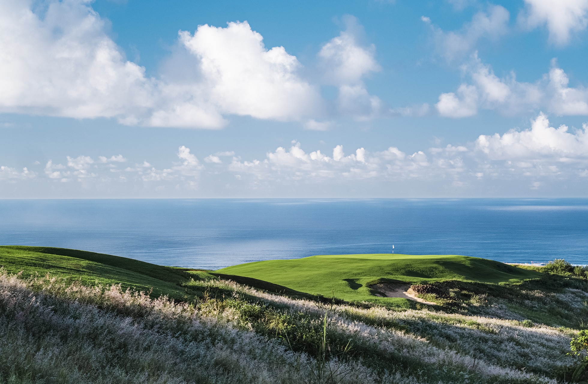 kystnær linksbane på heritage golf club la réserve golf links med grønne spilleflater på høyde og åpent hav i bakgrunnen