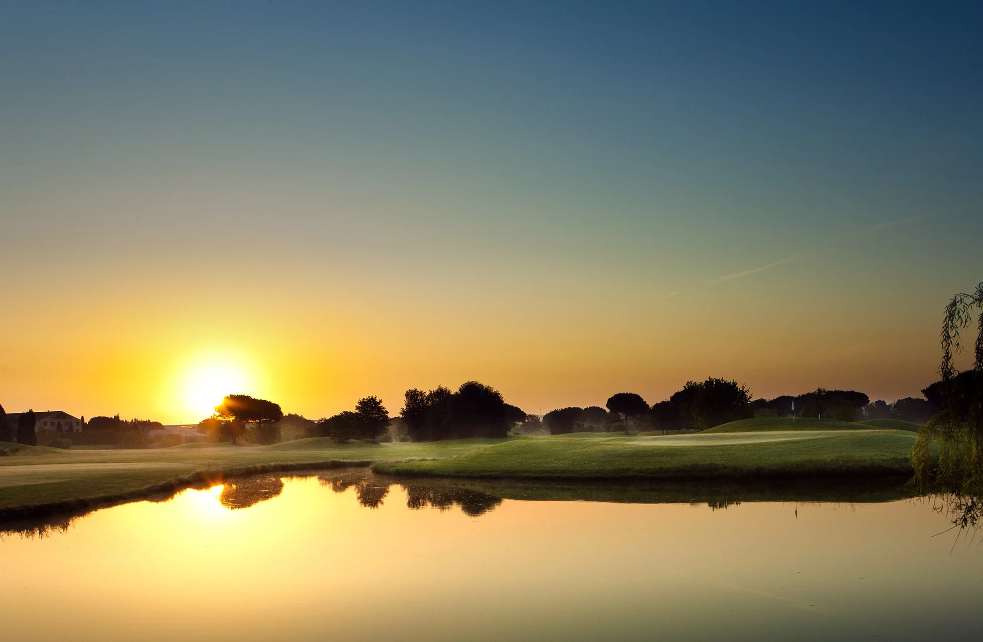 soloppgang over golfbanen på parco de’ medici golf club med stille vannhinder og åpne fairwayer