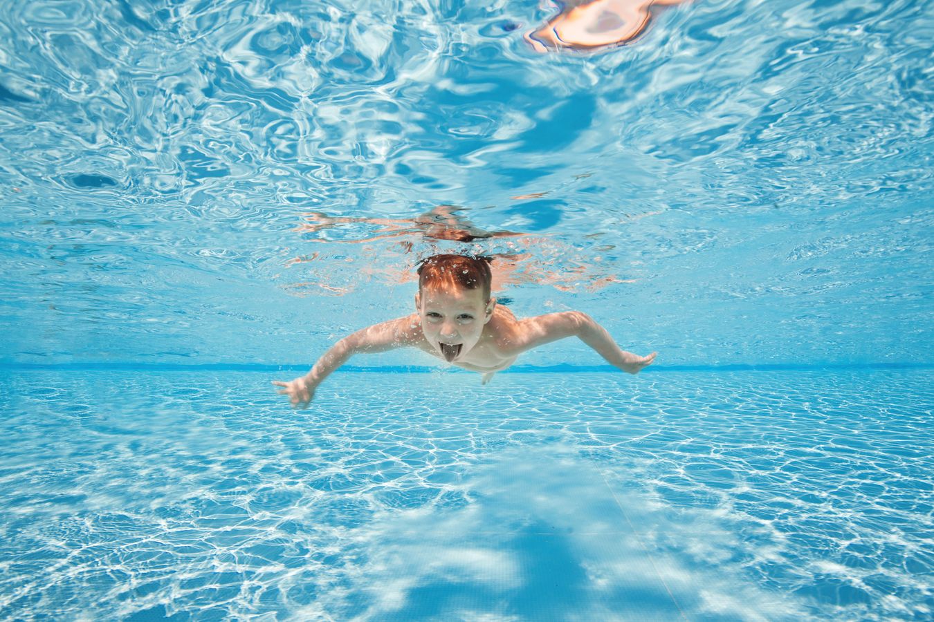 A young boy swimming underwater with his eyes open