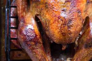 Chicken in a pan with dark background and oven glove