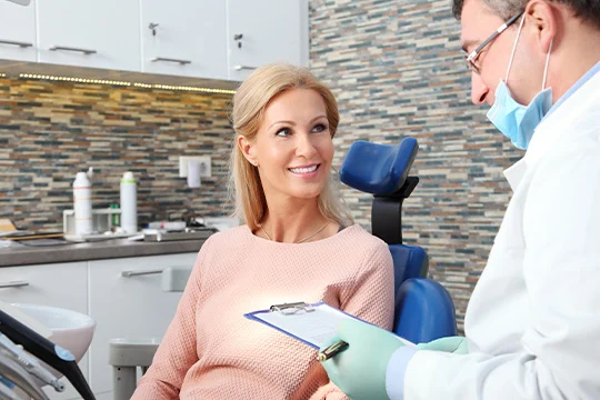 A male dentist explains what is going to happen in the tooth extraction process to a female patient.