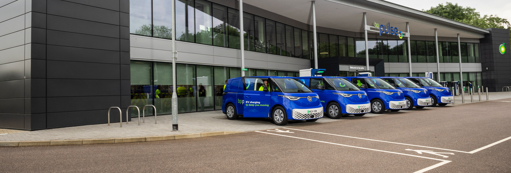 A row of bp pulse branded electric vans are lined up outside the bp pulse head office.