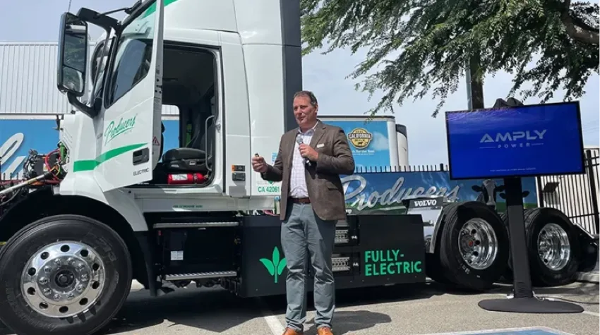 A man speaking on a mic in front of a Volvo VNR electric truck deployed in California’s Central Valley.