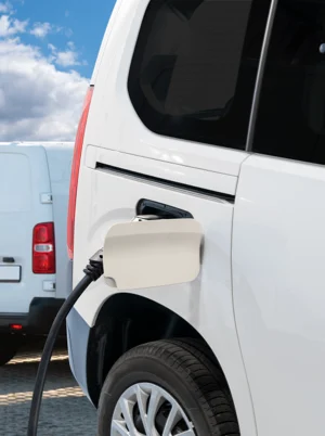 An EV charging cable is connected to the port of a white Electric Vehicle. Only the rear side of the Electric Vehicle where the charging port is located is visible.