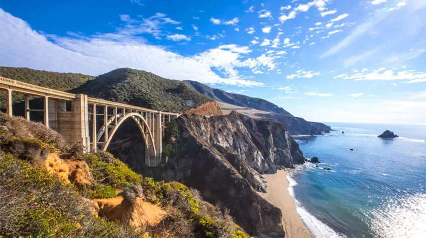 Rugged rocks and a bridge, overlooking the water, in California, at twilight.