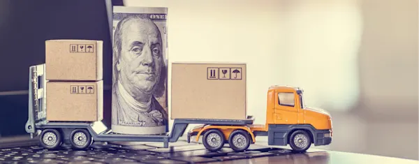 A toy van holding a rolled up dollar note. 
