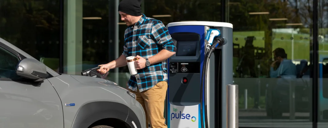 A man charging his EV on a sunny day.