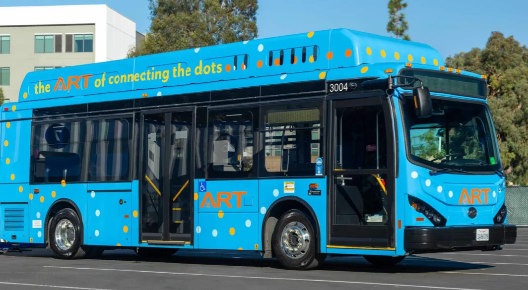 A bright blue Anaheim Transportation Network bus with orange and white polka dots, featuring the slogan 'the ART of connecting the dots' on the side.