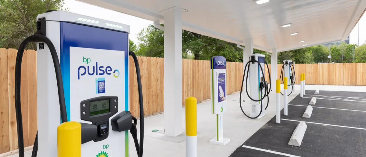 A row of bp pulse electric chargers sit behind vehicle parking bays ready to charge EVs.