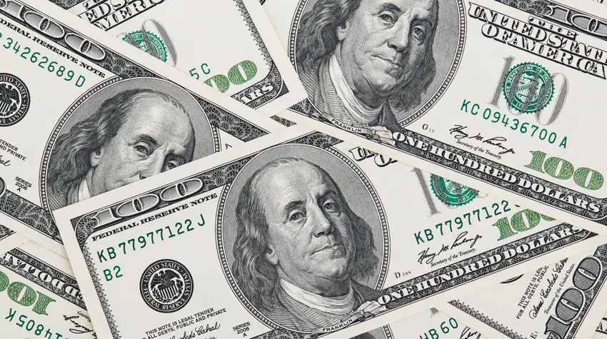 Few 100 US dollar currency notes spread across a flat surface.