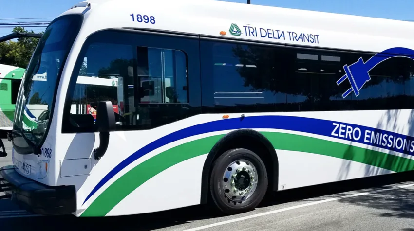 The side of a white, blue and green EV bus. 