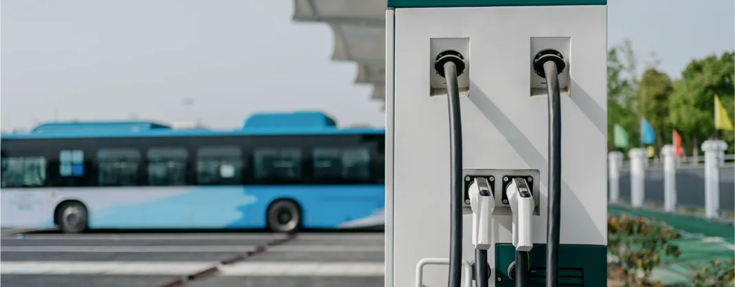A blue bus behind a charging point, which is not being used. 