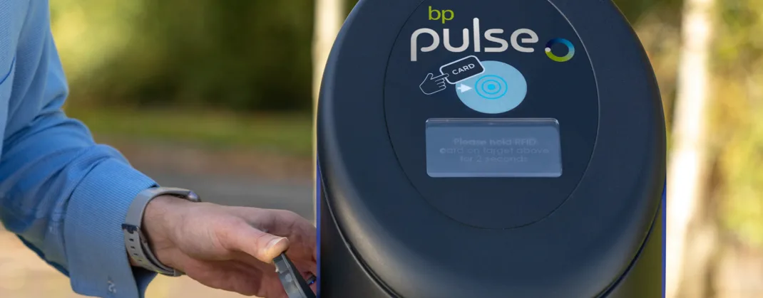 A person wearing a blue shirt scanning a bp pulse card at a bp pulse charger.