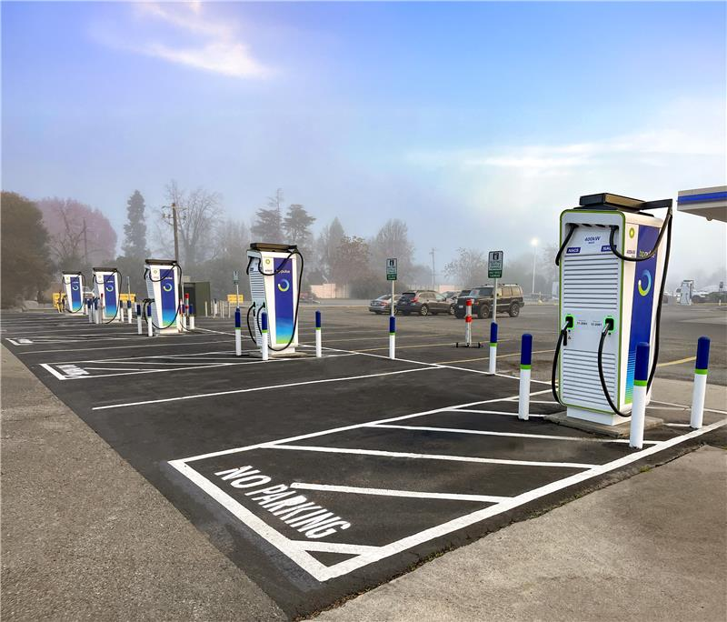 A row of five bp pulse EV chargers at a charging site in the US. In the background there are vehicles parked in parking bays.