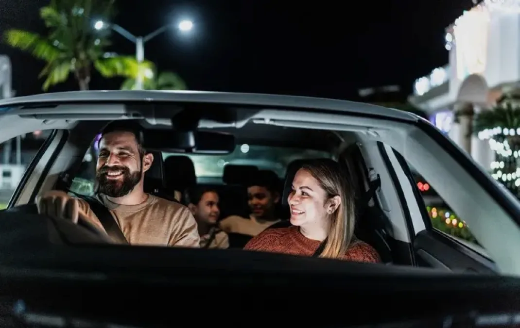 A family of four are having a good time in a car, in the night. 