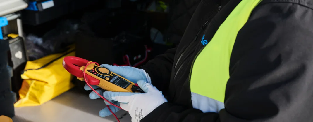 A technician using a device to inspect an EV charger.