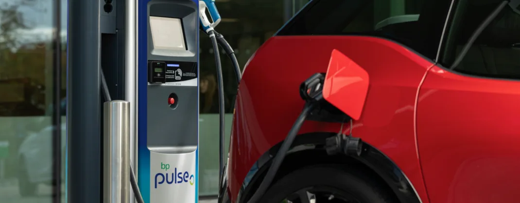 Red electric car charging at a bp pulse charge point. 