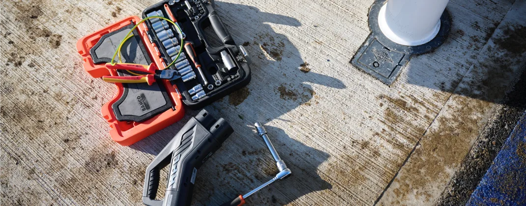 Few EV charging technical tools lay on the ground on a sunny day. 