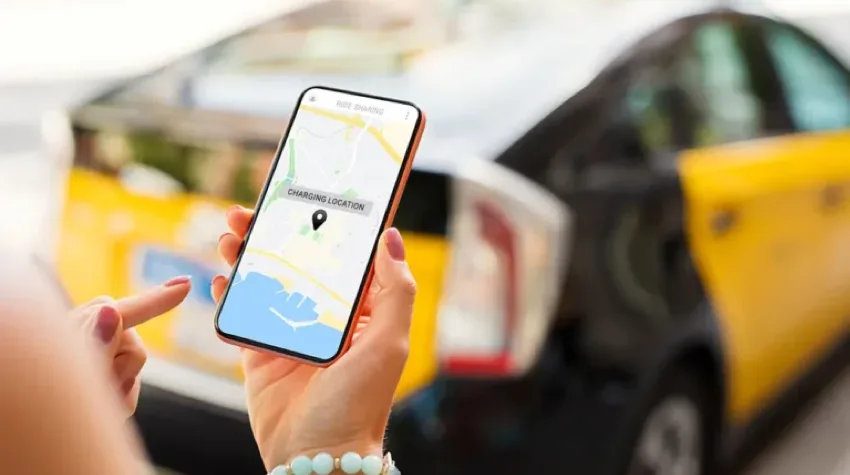 A hand holding a phone looking at a map, in front of an EV. 