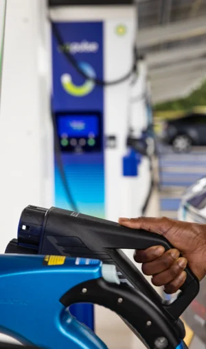 A hand is placing the Electric Vehicle charging cable back into its place on the bp pulse charger.