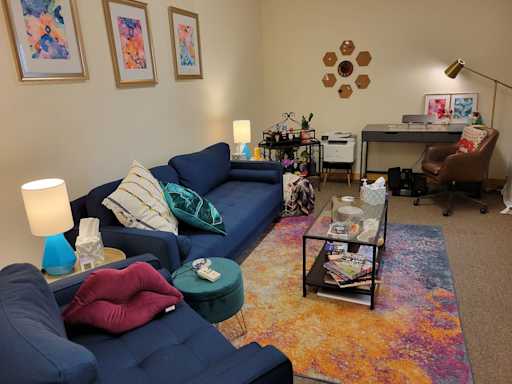 A wide view of the office with couch, desk, chair, and coffee table.