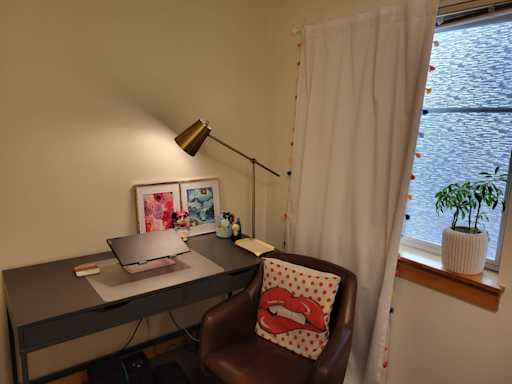 View of desk with chair next to a window.