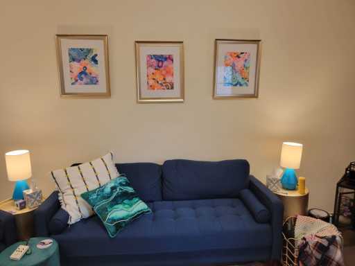 A view of a blue couch with flower paintings in the background.