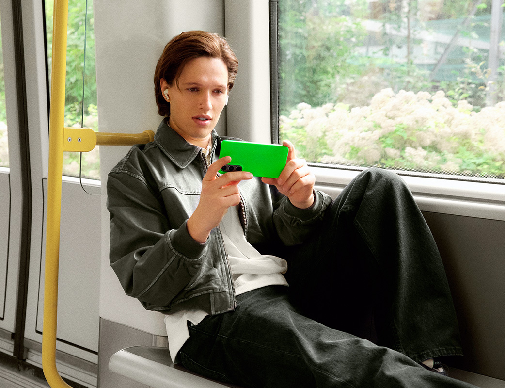 En ung mand kører i metro og ser på sin mobiltelefon