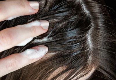 A woman with long brown hair massaging her scalp with her fingers A woman with long brown hair massaging her scalp with her fingers