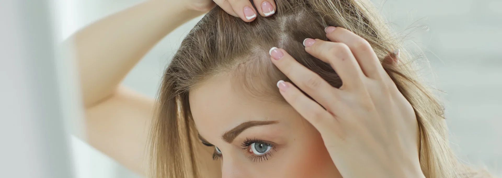Woman with long blond hair checking her part in the mirror