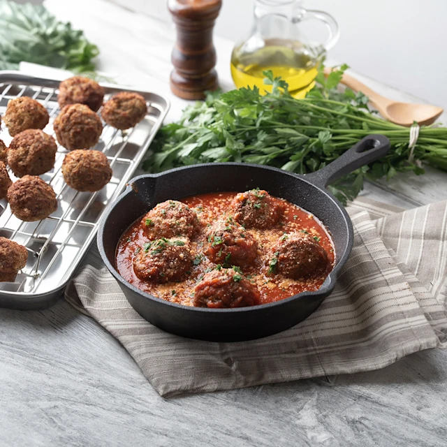 Aerial view of spiced meatballs with tomato sauce and herbs