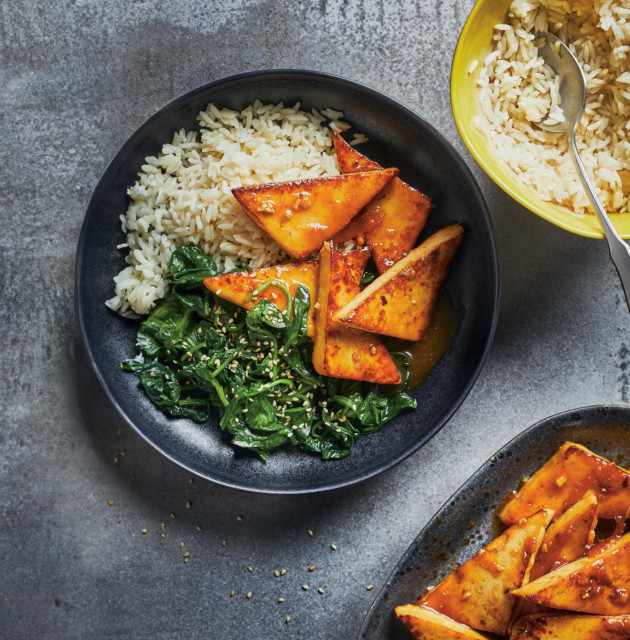 A plate of Ginger and orange-glazed tofu, served with rice and sauteed spinach