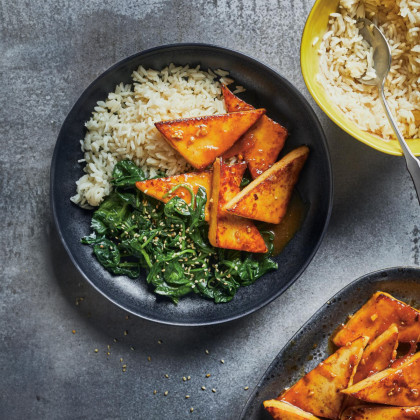 A plate of Ginger and orange-glazed tofu, served with rice and sauteed spinach