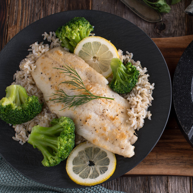 Steamed Ginger cod on a plate with rice, vegetables and lemon slices