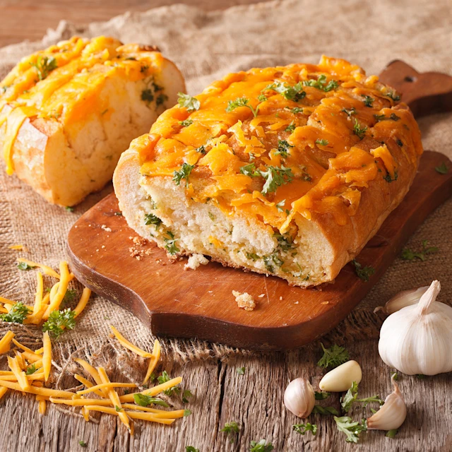 A sliced loaf of Cheddar-Herb Quick Bread on a cutting board