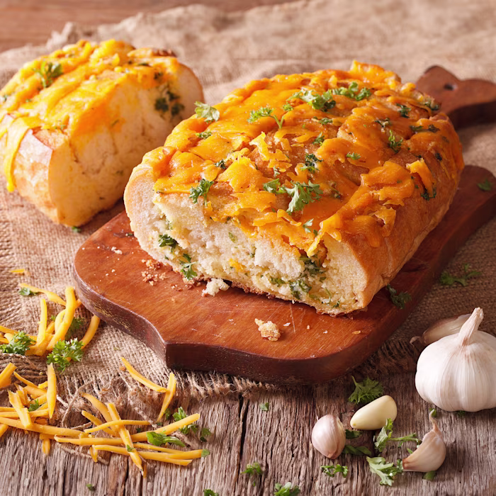A sliced loaf of Cheddar-Herb Quick Bread on a cutting board
