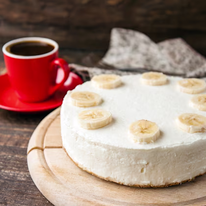 Banana coconut cake on wooden board with coffee in a red mug on the side