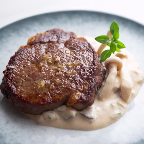 Aerial view of a plate of beef medallions with wild mushroom cream sauce