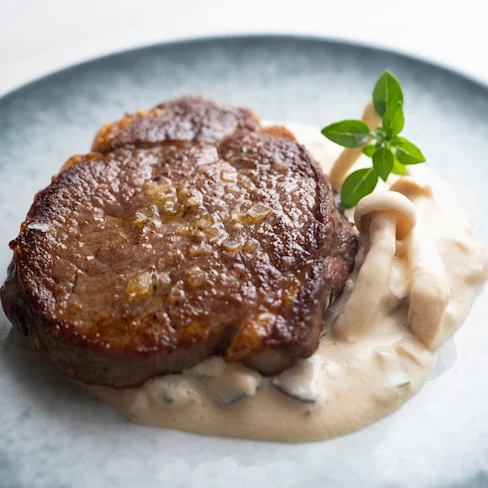 Aerial view of a plate of beef medallions with wild mushroom cream sauce