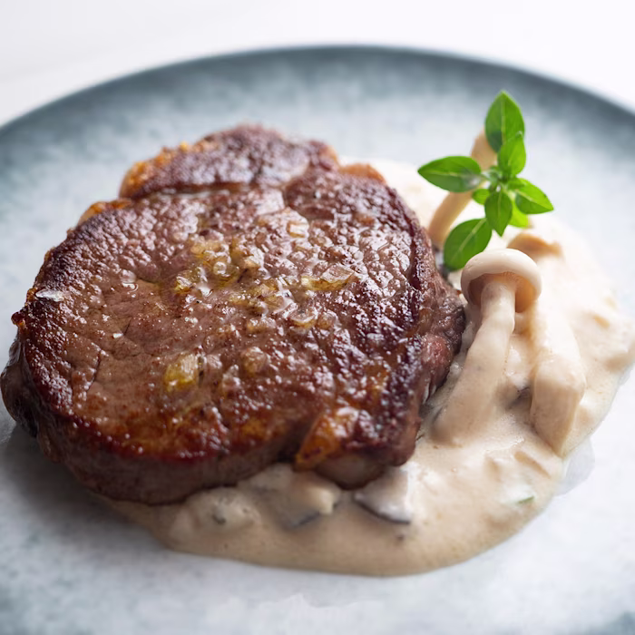 Aerial view of a plate of beef medallions with wild mushroom cream sauce