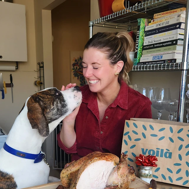 Chef Jill and her dog next to a sliced turkey
