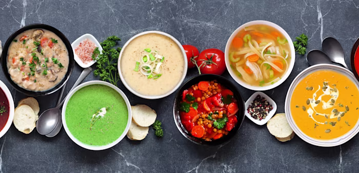 Image of a variety of homemade soups on a dark slate background