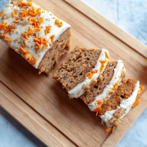 A sliced carrot cake with maple cream cheese icing on a serving board